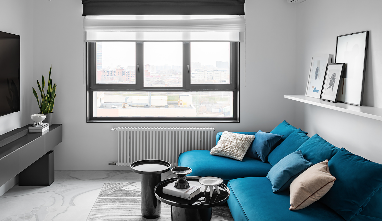 salón pequeño con sofá azul y mesas auxiliares negras.