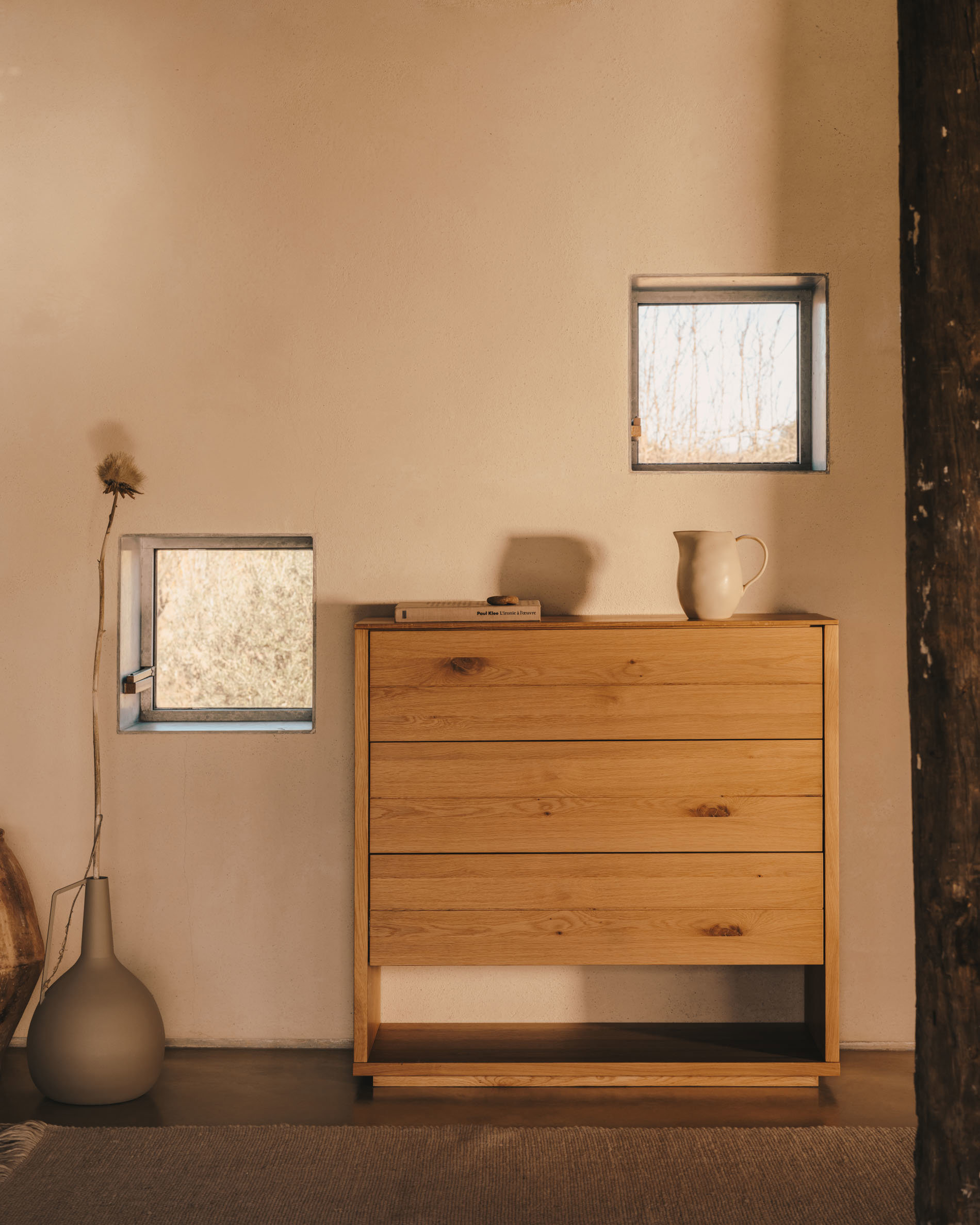 Cómoda en madera natural en una habitación de paredes en beige y hornacinas 