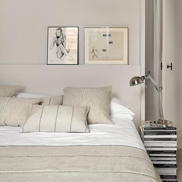 Dormitorio gris con libros como mesita de noche