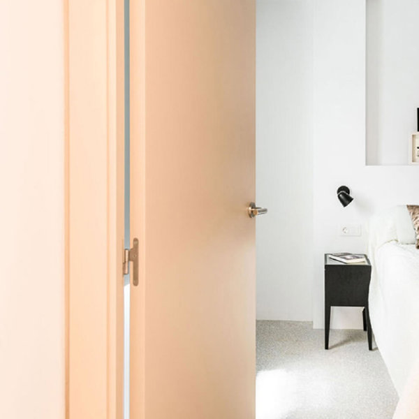 Dormitorio minimalista en color blanco y con puerta rosa