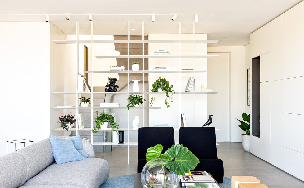 Salón con estantería blanca que hace de separador de espacios.
